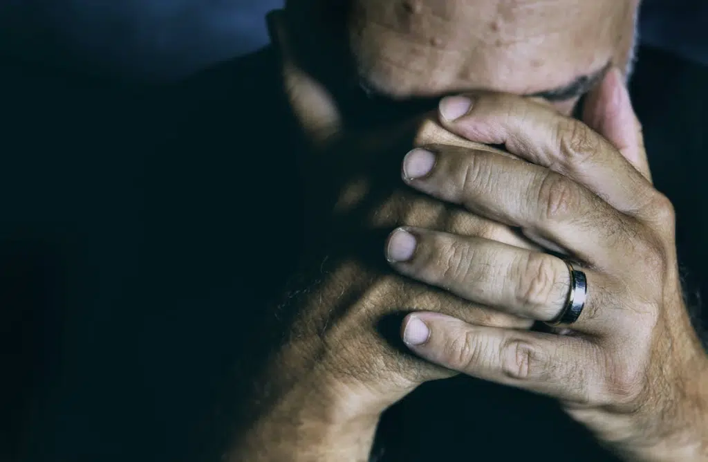 A sad man covering his face