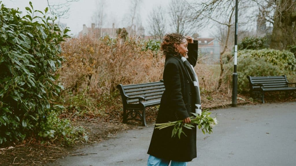 A woman holding flowers looking toward the distance.