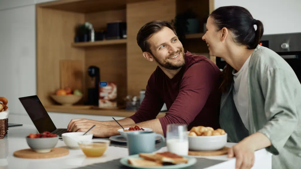 A couple smiling at each other in the kitchen