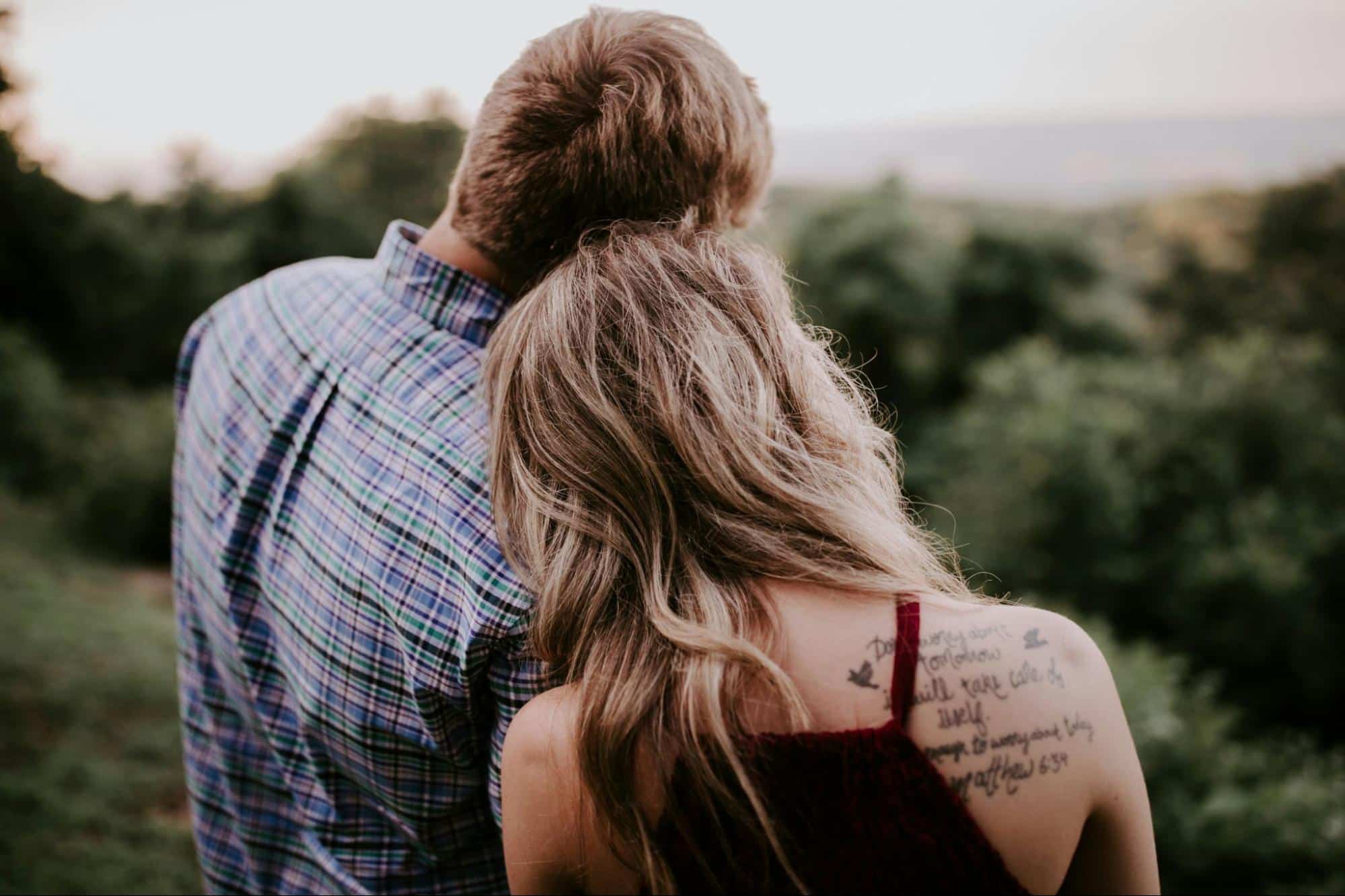 A woman resting her head on man’s shoulder 