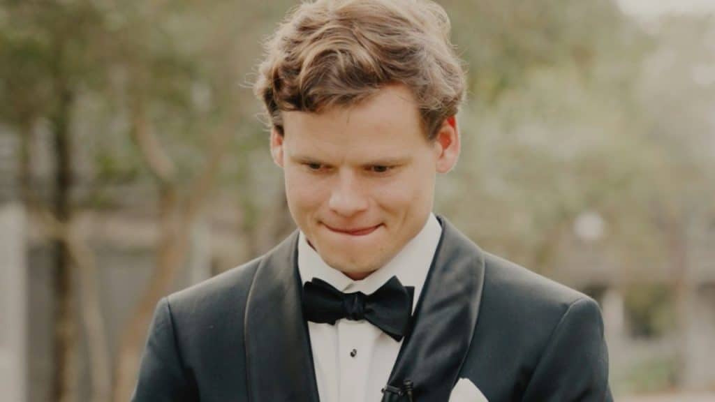 Close-up of a nervous-looking man in a black tuxedo and bow tie outdoors.