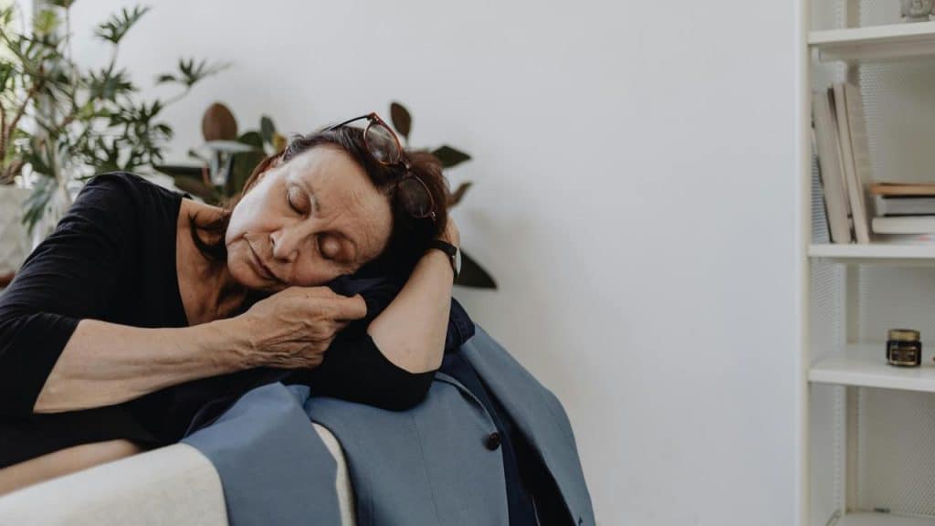 A woman sleeping while leaning on a folded jacket in a cozy indoor space.