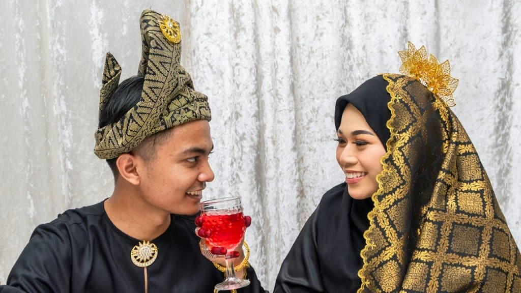 A woman giving her husband a special beverage on their wedding day.