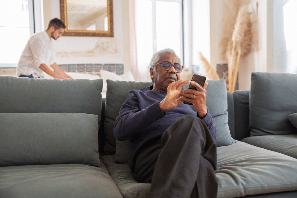 Elderly Man Sitting on the Couch while Holding His Cellphone