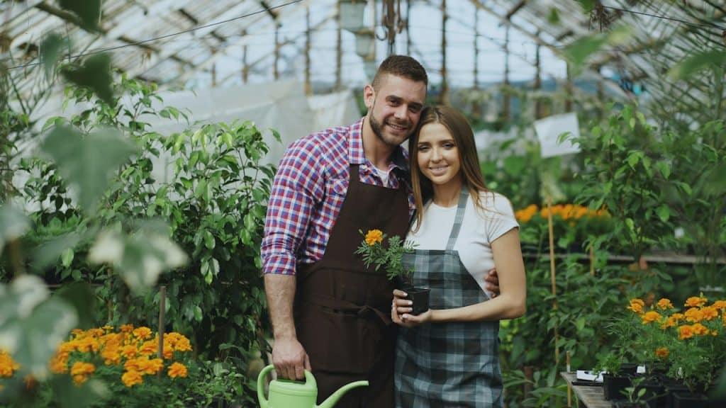 A couple standing and smiling inside a greenhouse. 