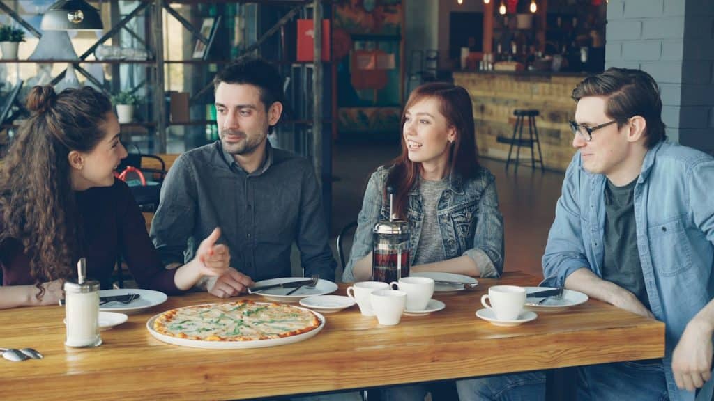 A group of friends talking while having pizza.