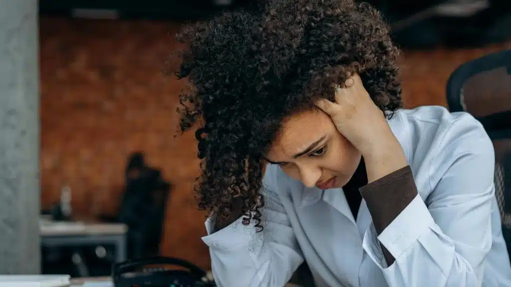 A woman holding her head in her hands while looking down in frustration or stress.