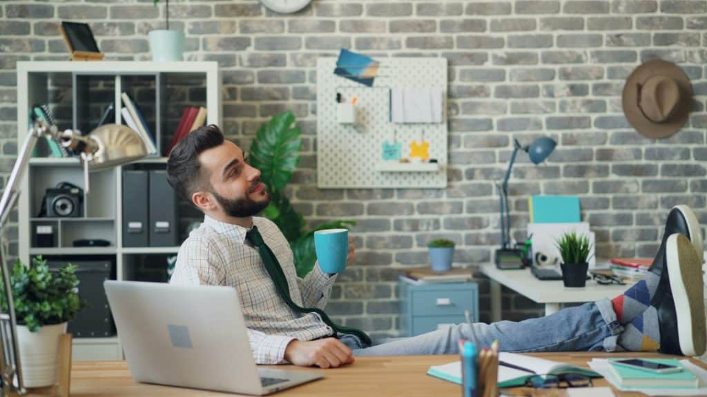 A man sitting in front of a laptop while holding a cup of coffee.