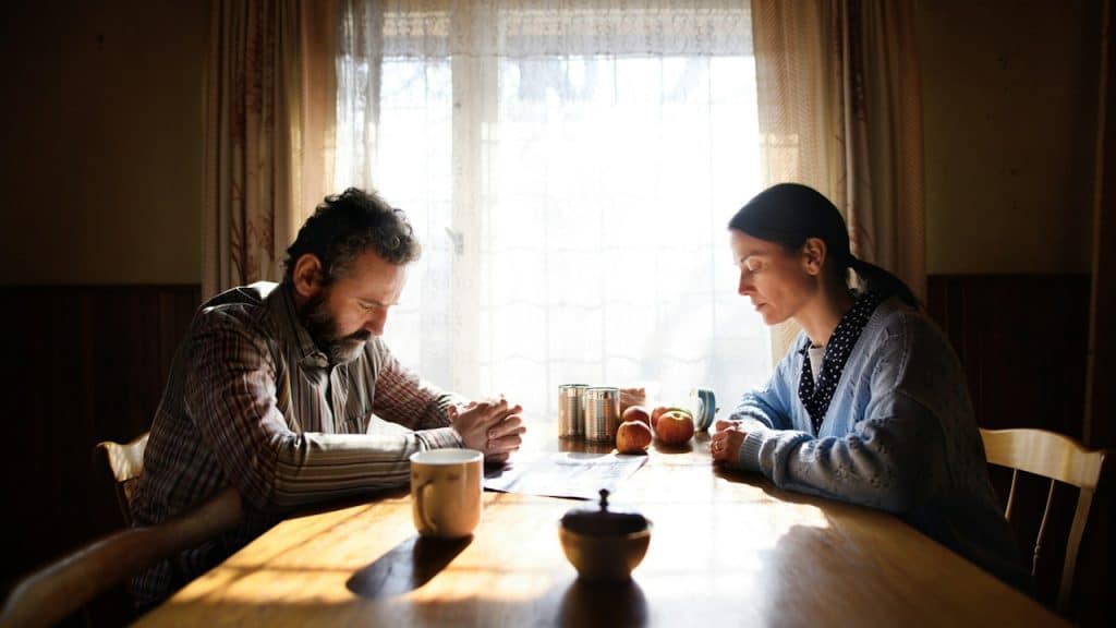 A sad couple sitting at a dinner table silently.