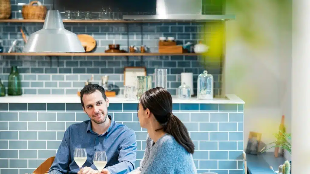 A man and a woman conversing in the kitchen.