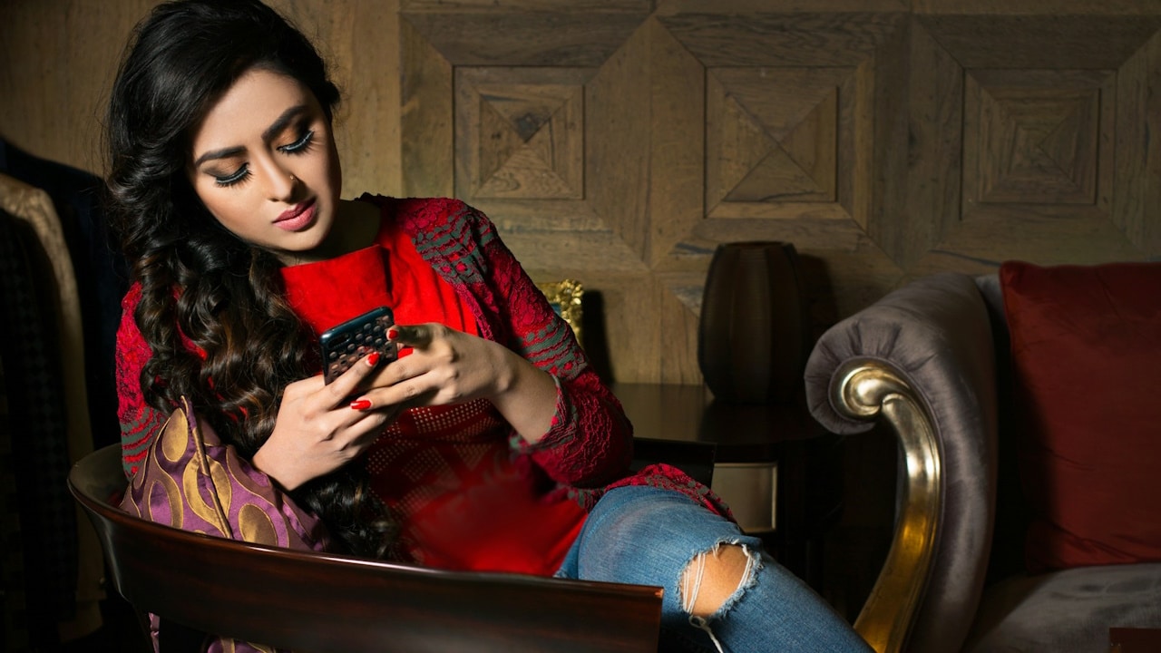 A woman sitting on a couch and using her phone.
