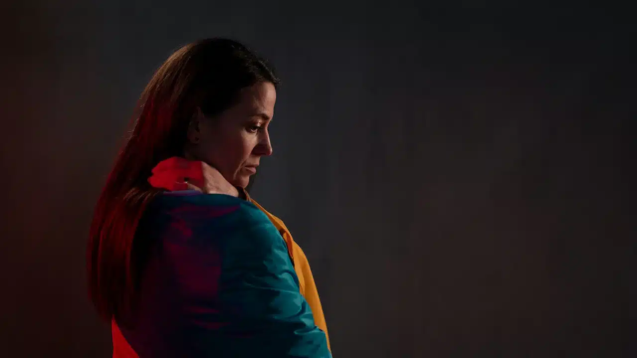 A sad woman standing in a dimly lit room.