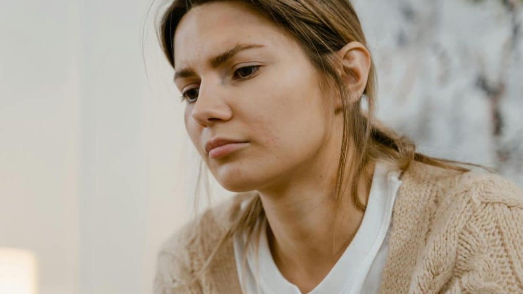 A woman looking down with a serious expression.