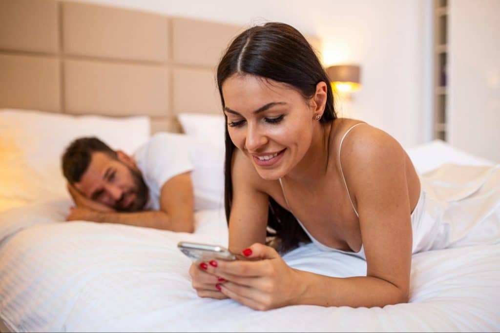A man looking at the woman busy with her phone