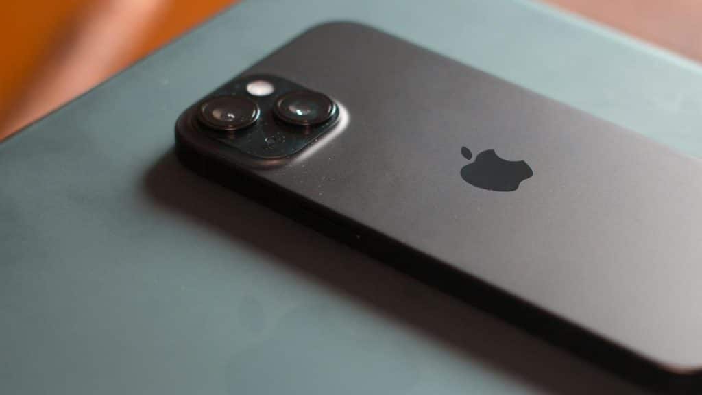 A black iPhone with dual cameras placed on a flat surface.