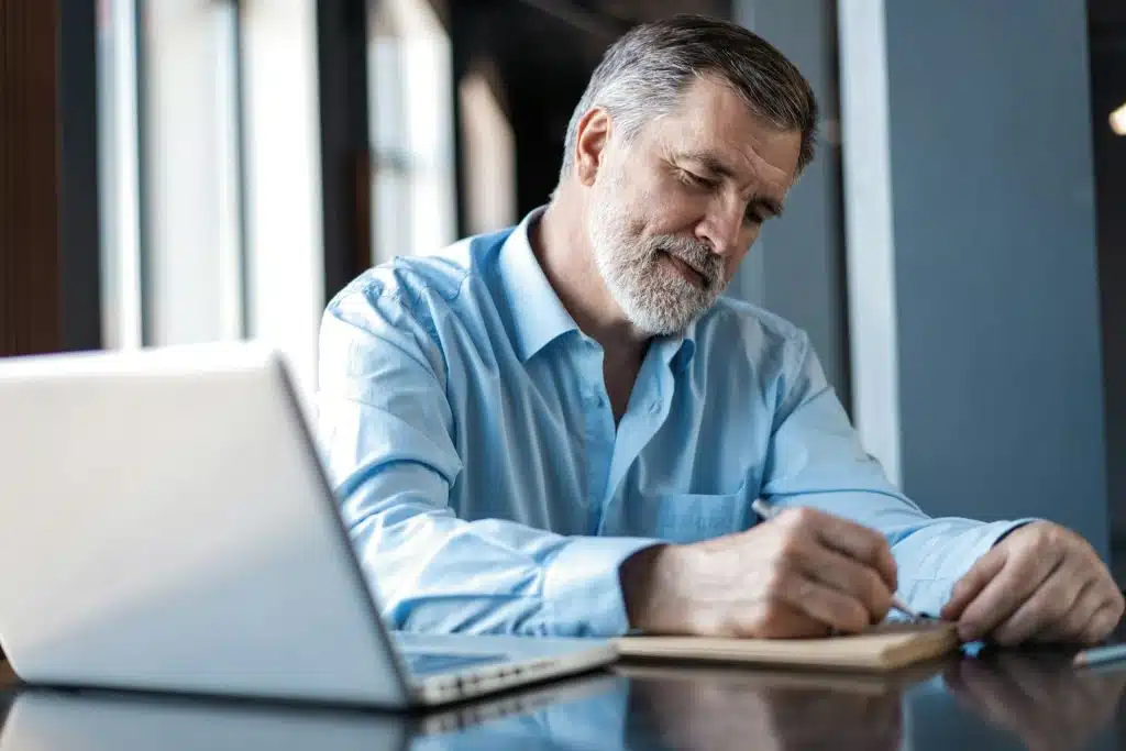 A businessman writing something on a notepad.