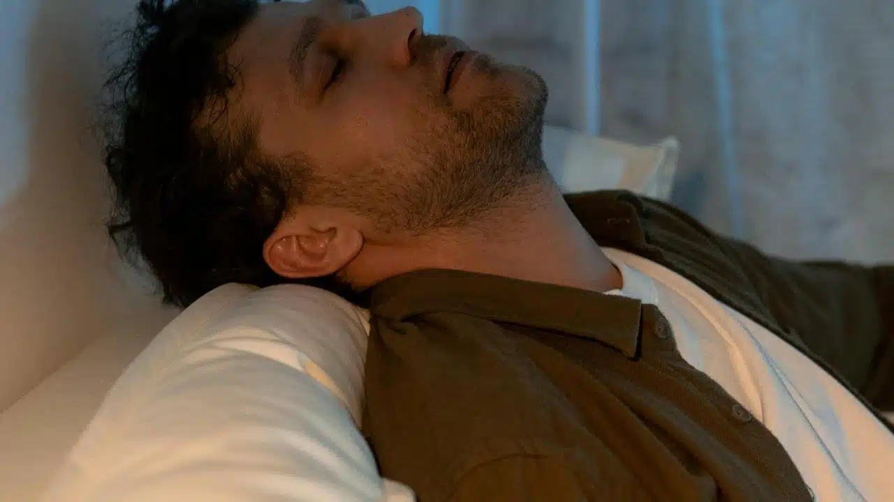 A man resting with his head tilted back on a pillow.
