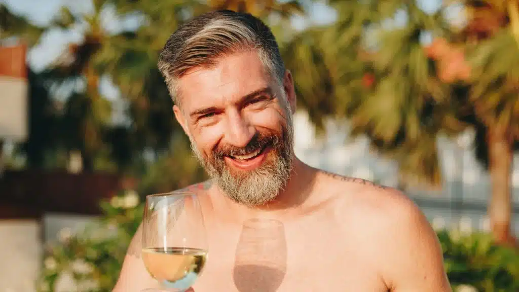 A handsome man having a glass of wine in the pool.