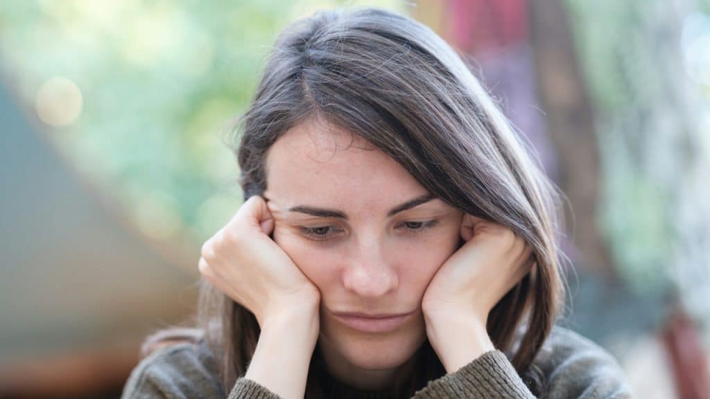 A woman looking upset with her face in her hands.