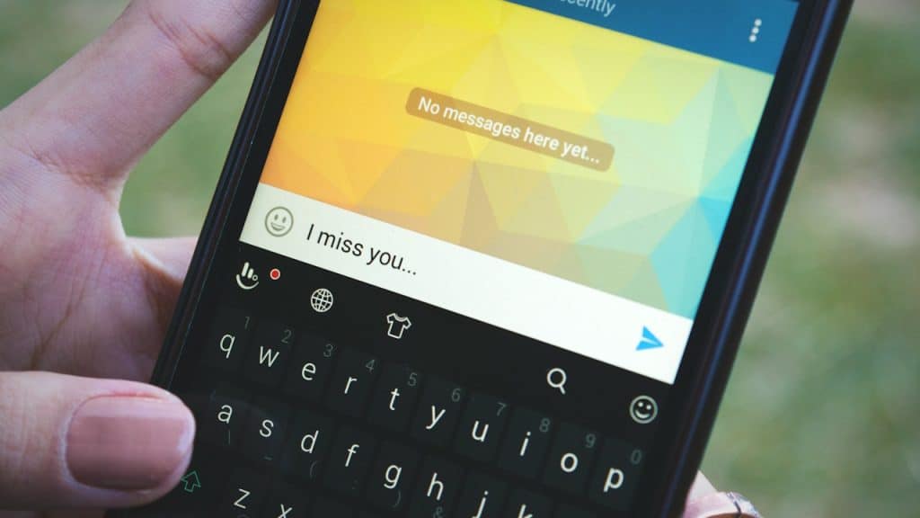 A close-up of a person holding a smartphone, typing "I miss you..."
