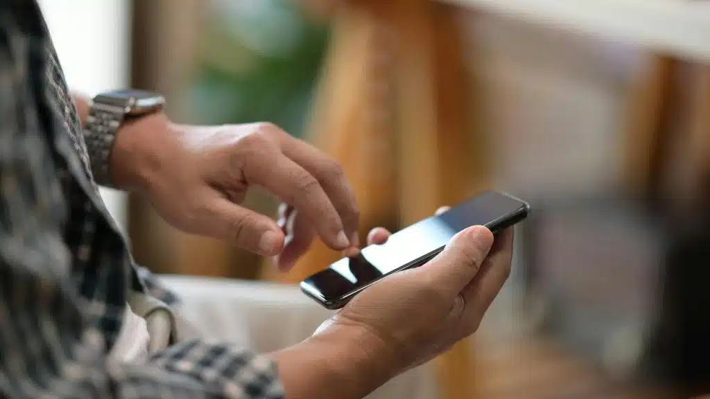 A person uses a smartphone while seated indoors.