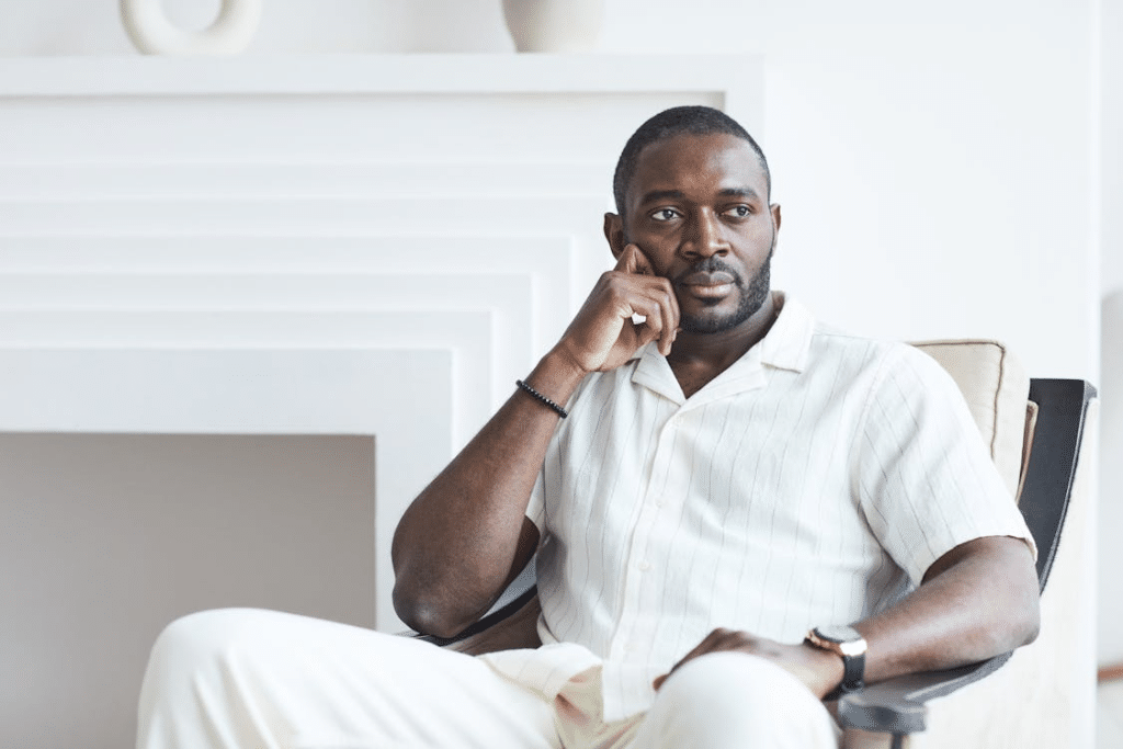 Man in White Clothes Sitting on an Armchair while Thinking