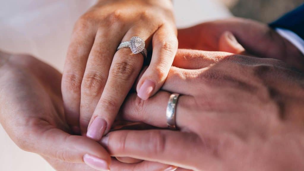 A close-up of a coupleโs hands showing their wedding rings.