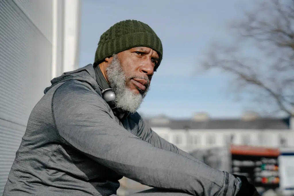 Thoughtful black man with headphones sitting outdoors