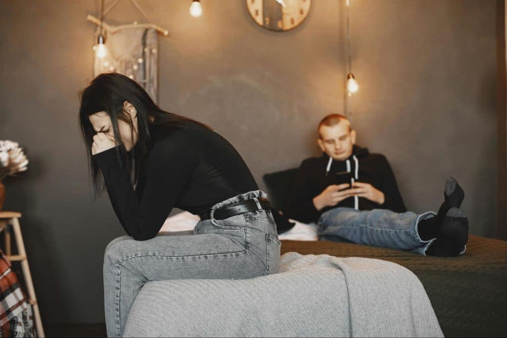 A man busy with his phone and a woman crying