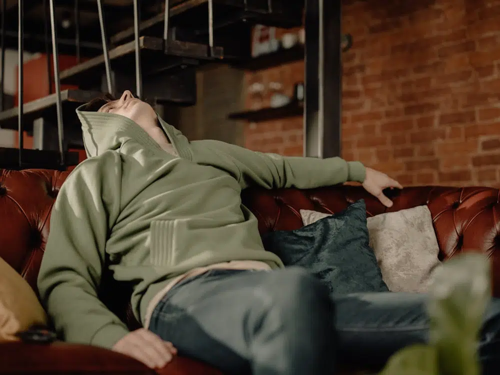 A man in a green jacket sitting on a couch