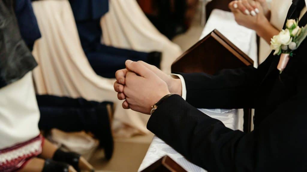 A groom and bride kneeling together during a wedding ceremony.