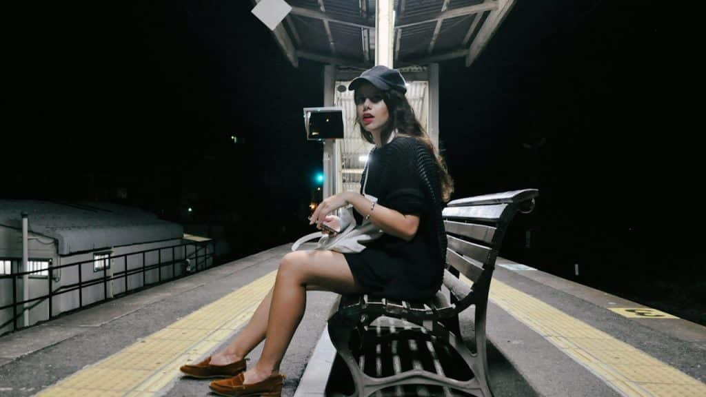 A woman wearing a black dress sitting on a bench.