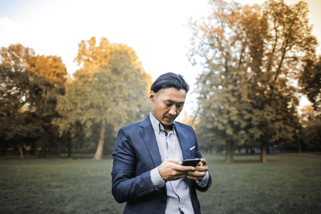 Photo of Man in Suit Jacket and Striped Shirt Using His Phone