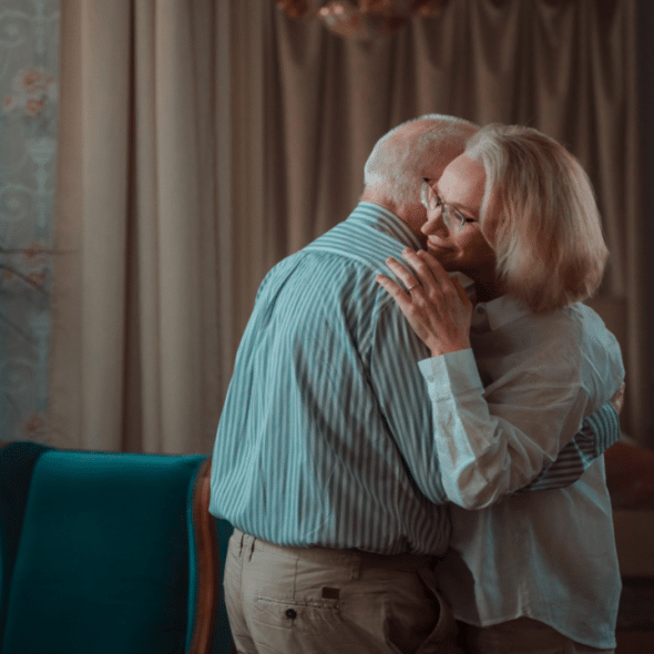 An elderly couple dancing at home