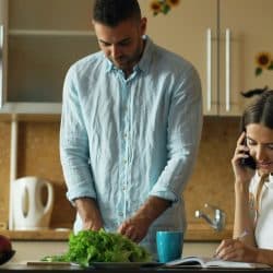 A couple ignoring each other in the kitchen
