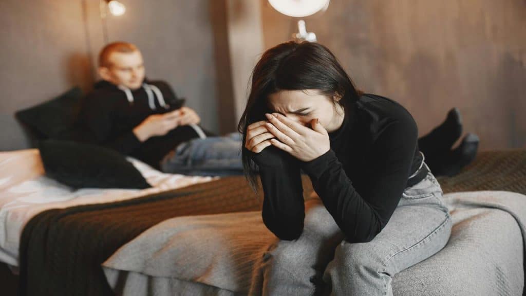 A woman crying while her husband is busy with his phone