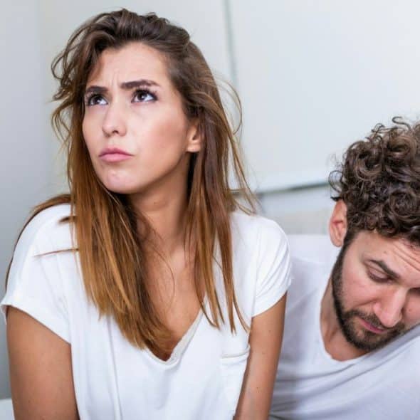 Woman looking up with a worried expression, sitting next to a man looking down.