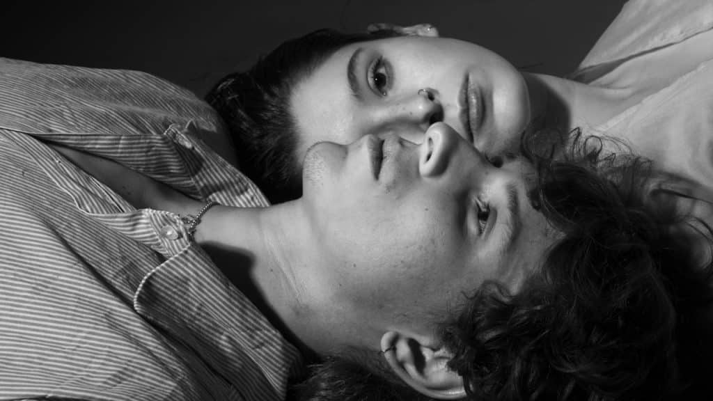 A young man and a woman lying next to each other.