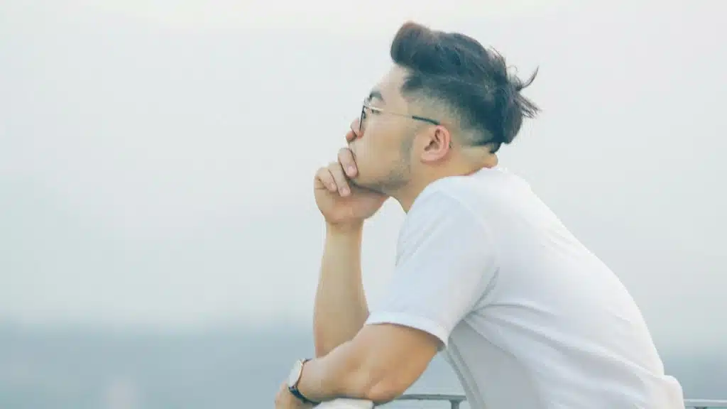 A man wearing glasses gazing into the distance.