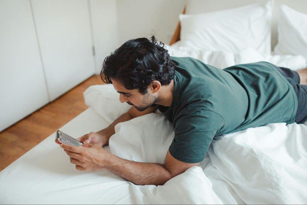 A man laying in bed and reading messages