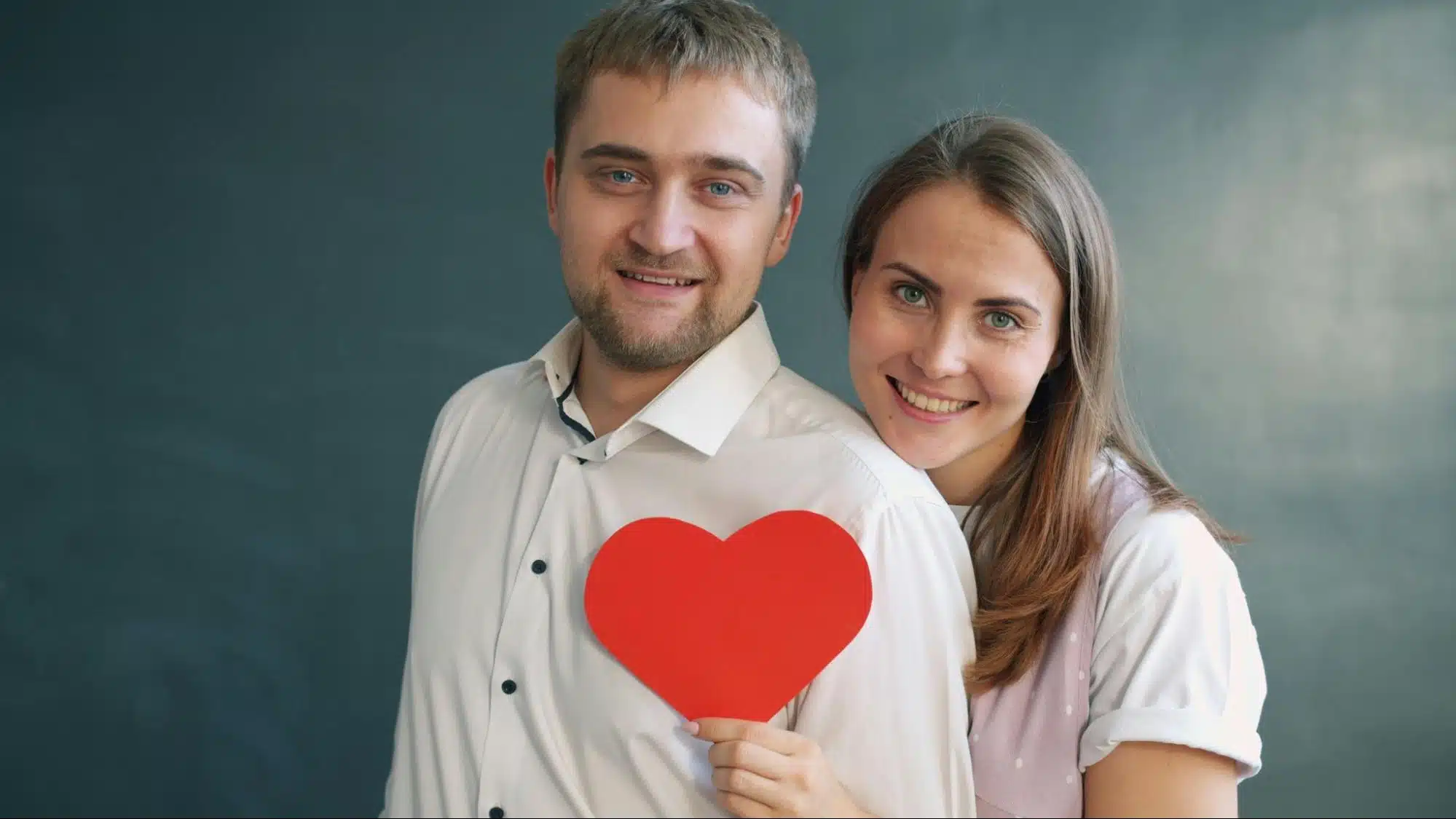 A man and woman holding a heart shaped paper 