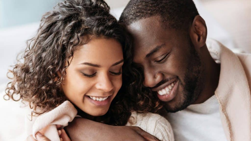 A man and a woman cuddling in the bed.