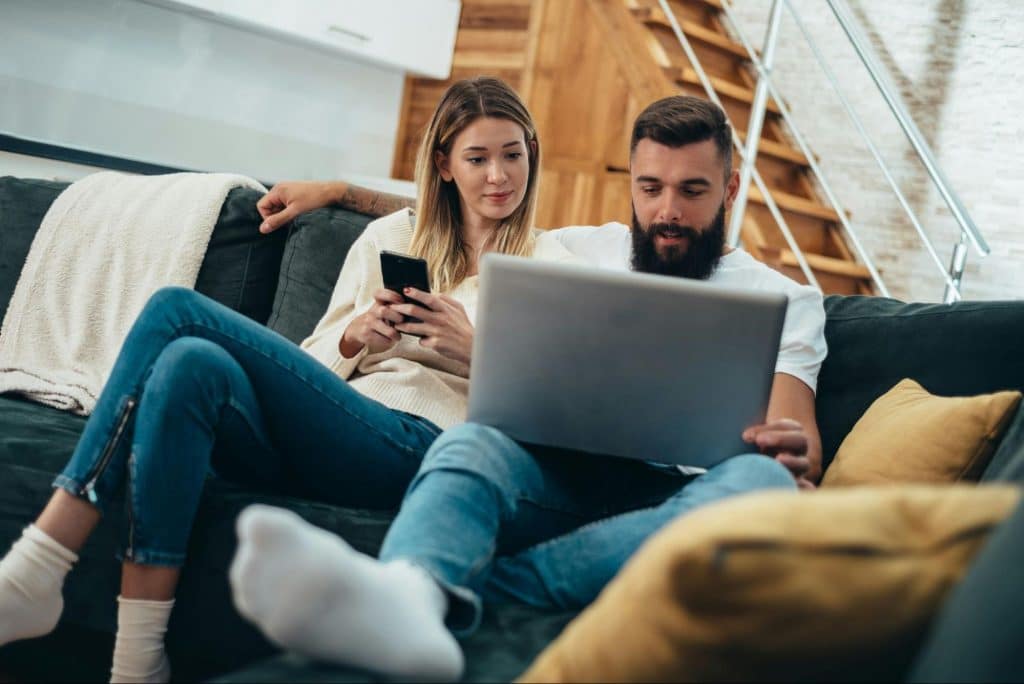 A woman looking at the man’s laptop 