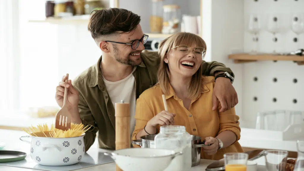 A couple laughing together in the kitchen