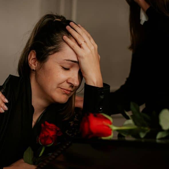 A sad woman sitting with her hands on her head.