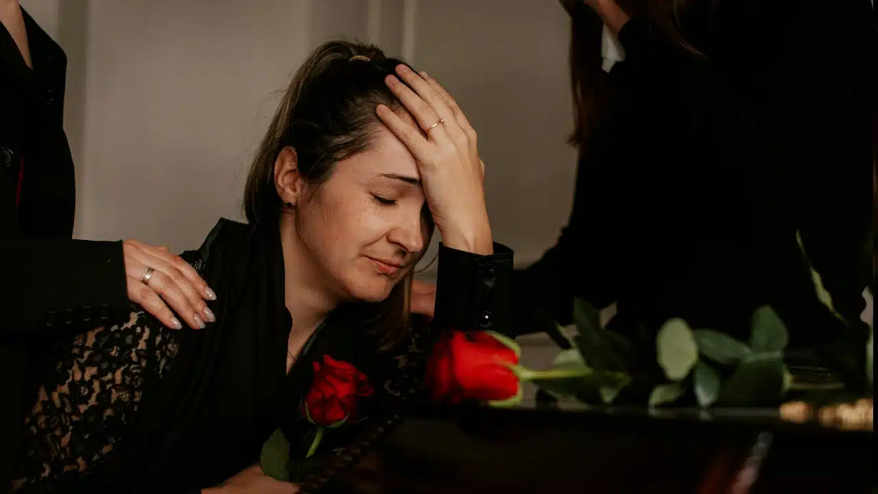 A sad woman sitting with her hands on her head.