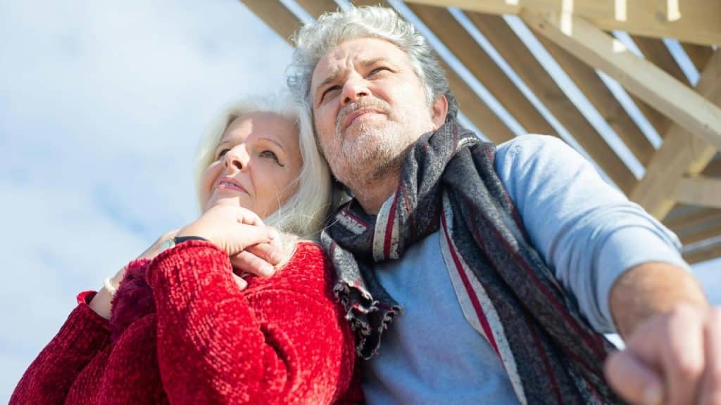An older couple outdoors looking thoughtfully into the distance.