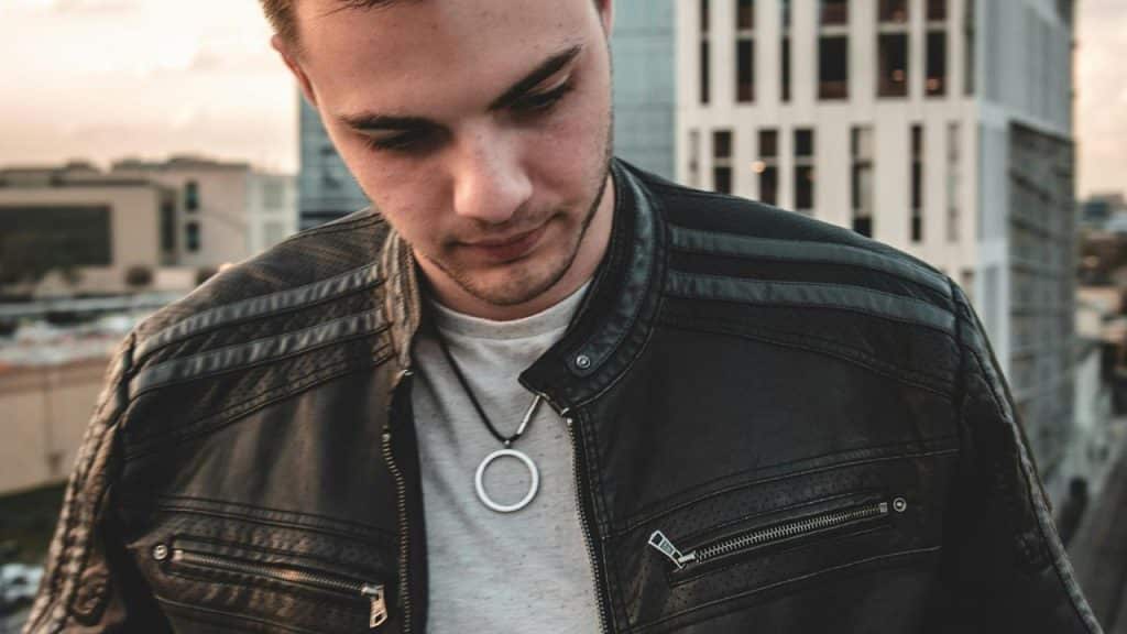 A man wearing a black leather jacket looking down.