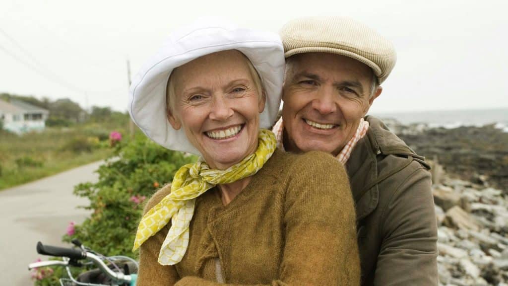 An older couple holding each other closely while sitting outside.