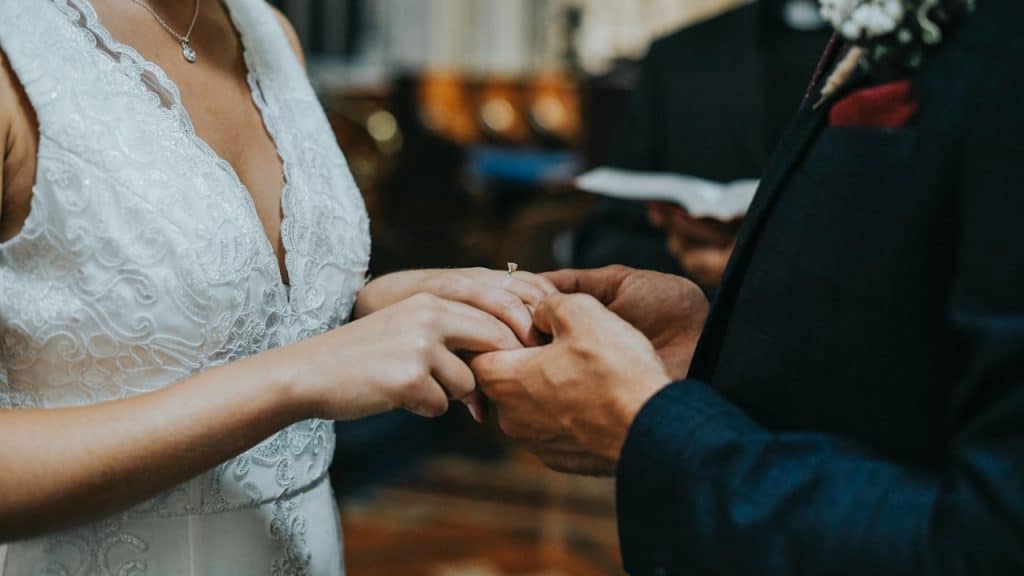 Close-up of a bride and groom holding hands.